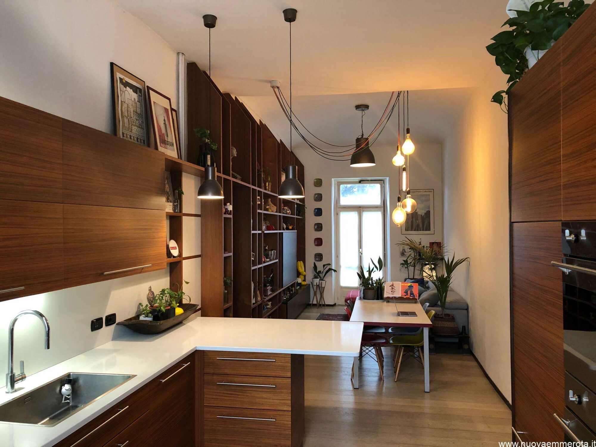 Open space zona living con cucina e libreria in legno teak.